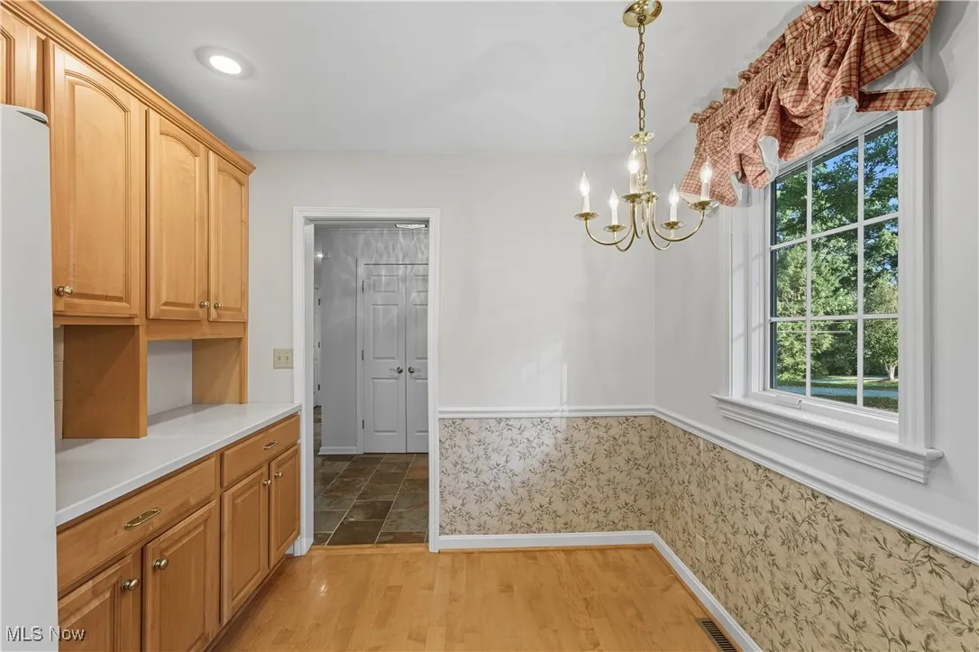 Kitchen featuring light wood finished floors, light countertops, pendant lighting, a chandelier, and freestanding refrigerator