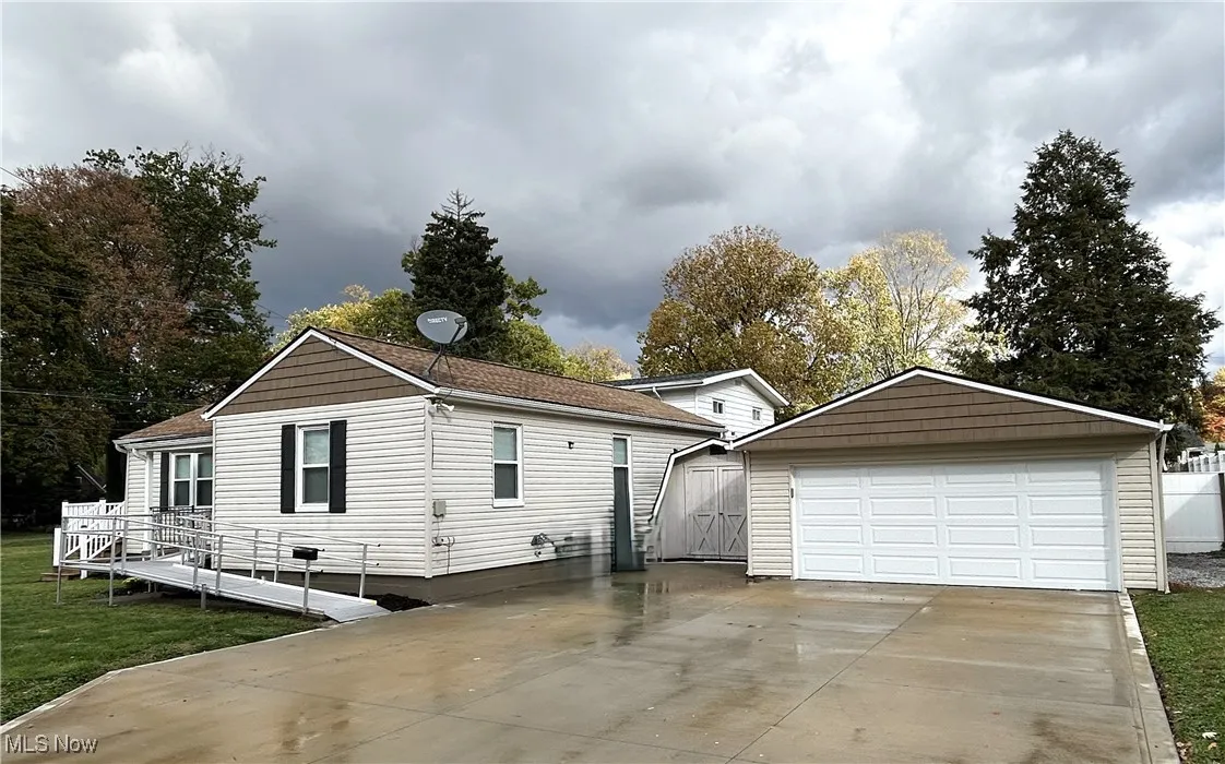 Garage with newer concrete driveway and a shed for additional storage.