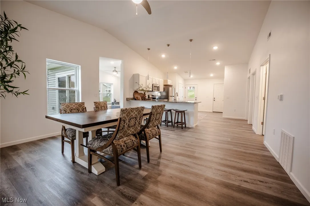 Dining area with lofted ceiling, light wood-style flooring, recessed lighting, and ceiling fan
