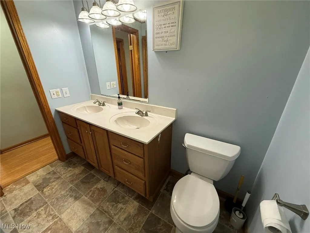 Full bathroom featuring double vanity, dark stone finish floors, and radiator heating unit