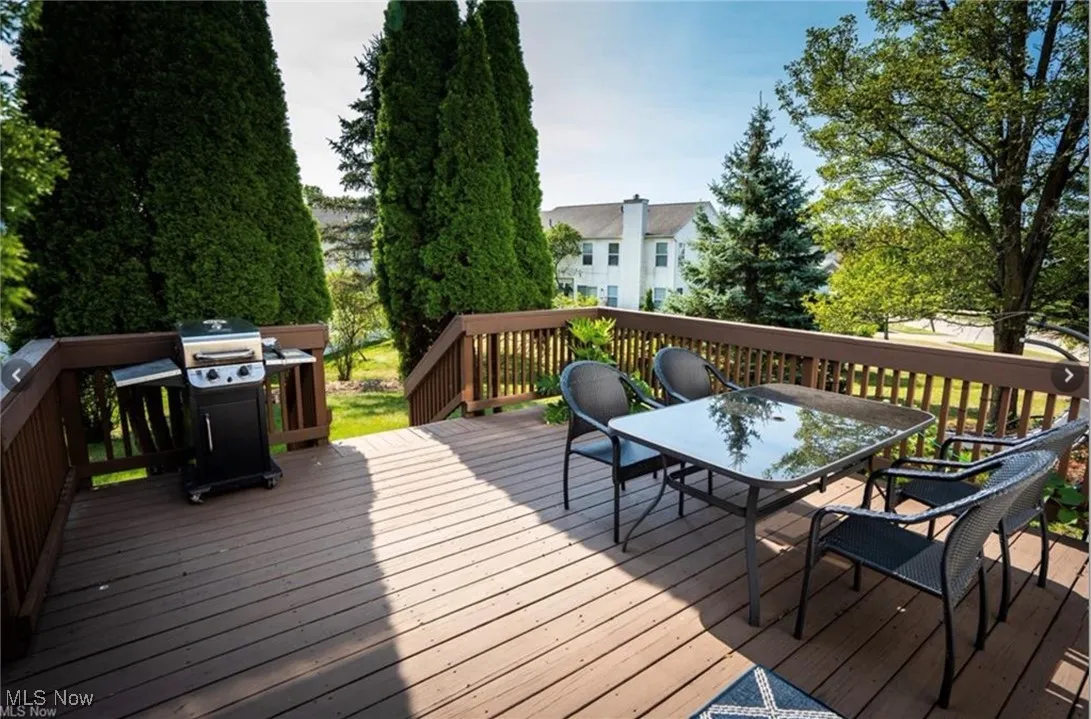 Wooden deck featuring outdoor dining space and a grill