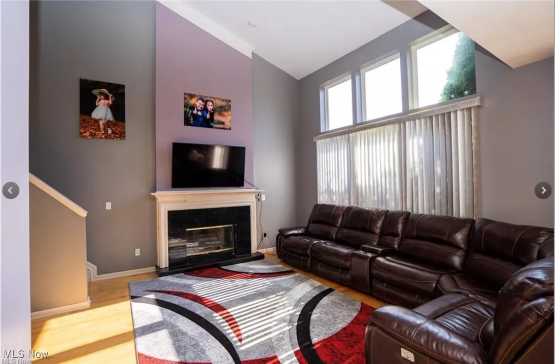 Living room with a premium fireplace, lofted ceiling, and wood finished floors