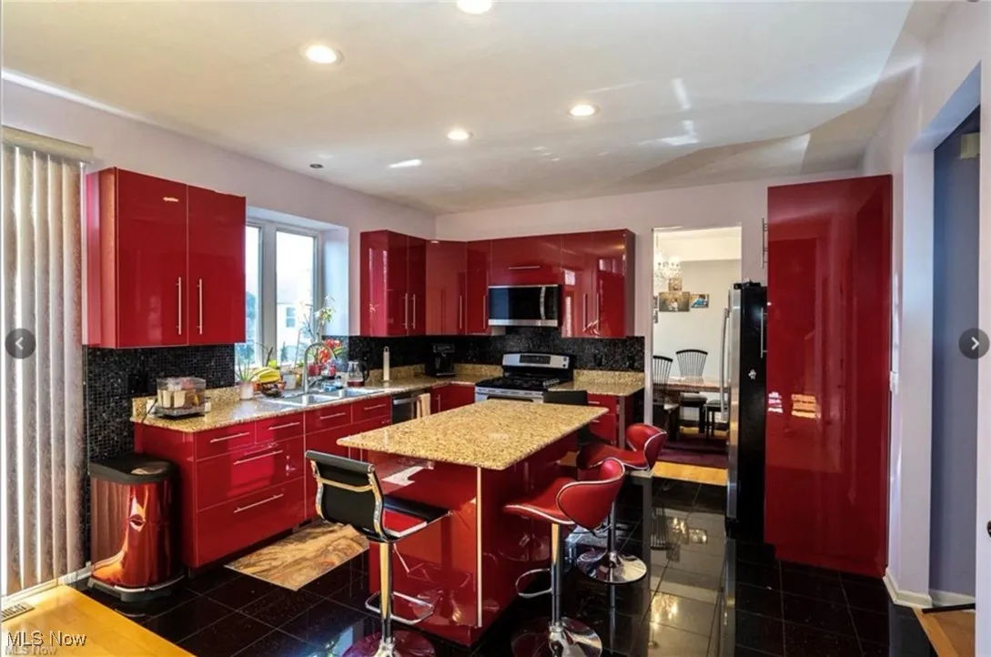 Kitchen featuring red cabinets, backsplash, appliances with stainless steel finishes, and recessed lighting
