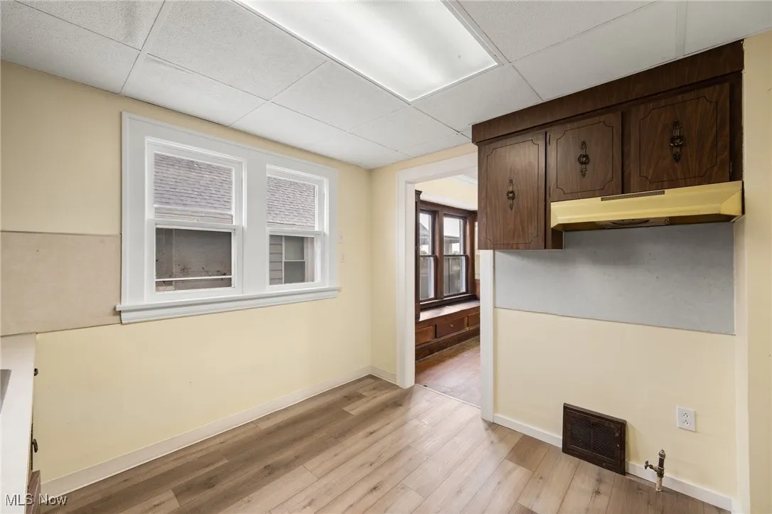 Unfurnished dining area with a drop ceiling and light wood-type flooring