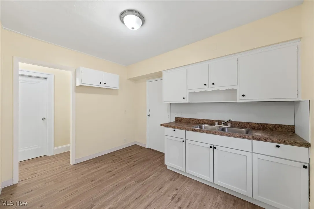 Kitchen featuring dark countertops, light wood-type flooring, and white cabinetry