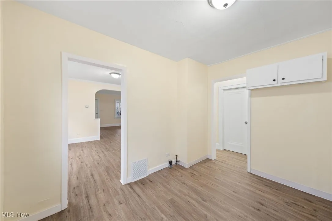 Spare room with light wood finished floors and arched walkways