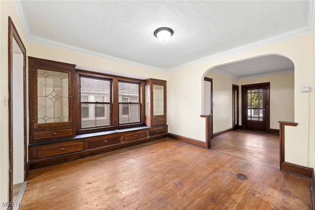 Spare room with ornamental molding, wood-type flooring, and arched walkways