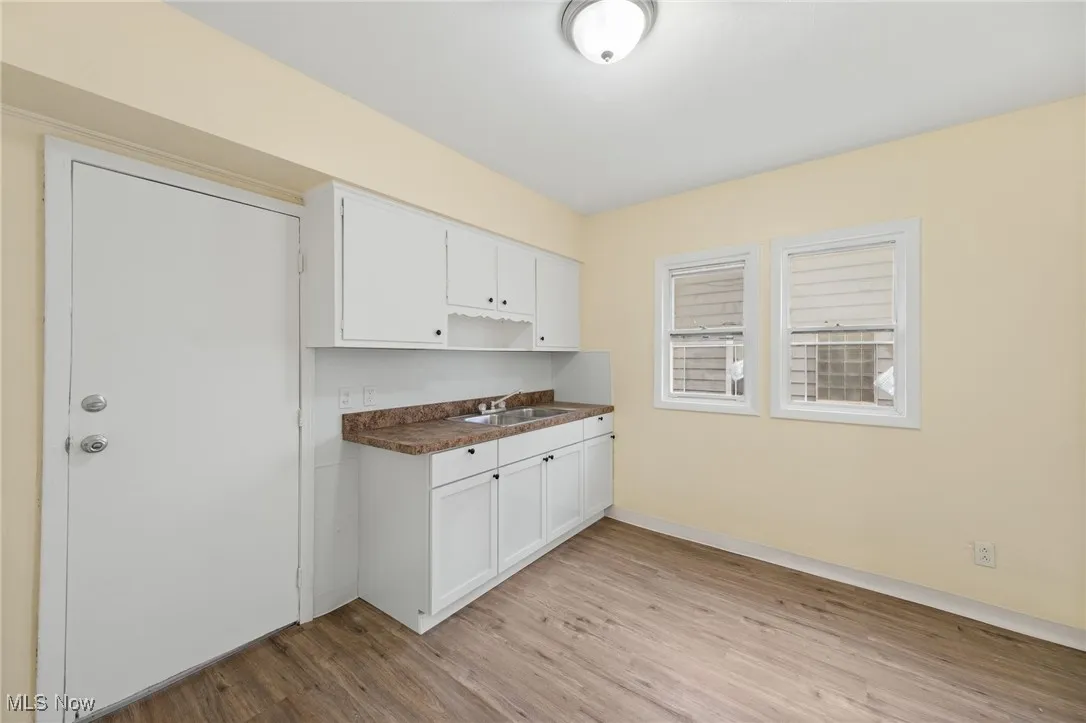 Kitchen featuring dark countertops, white cabinets, and light wood-style flooring