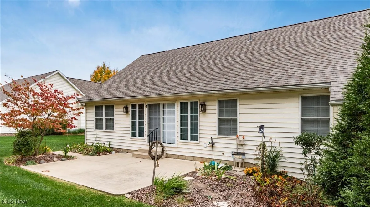 Rear view of house with a patio, a lawn, and a shingled roof