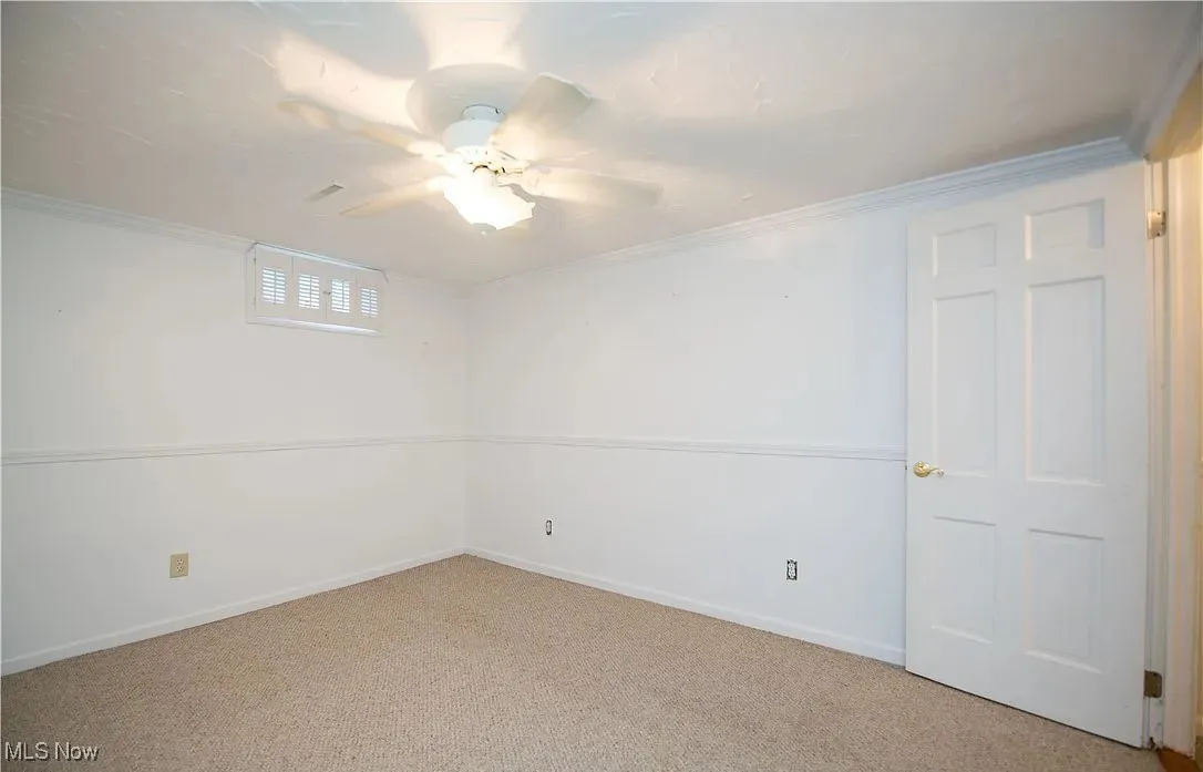 Basement featuring carpet flooring, ceiling fan, and crown molding