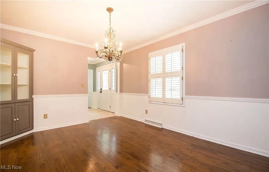 Unfurnished dining area featuring crown molding, dark wood-style flooring, and a chandelier