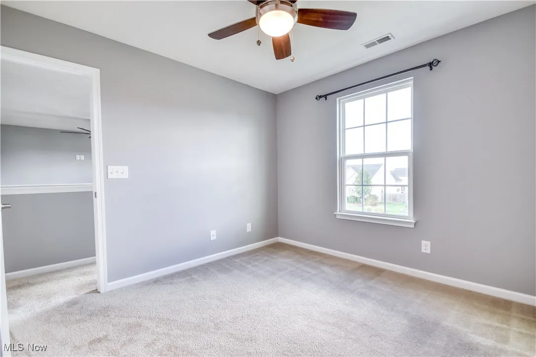 Unfurnished bedroom featuring light carpet and ceiling fan