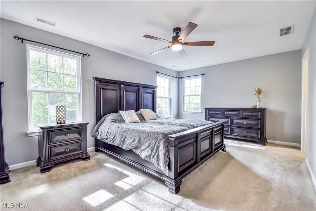 Bedroom with light colored carpet and a ceiling fan