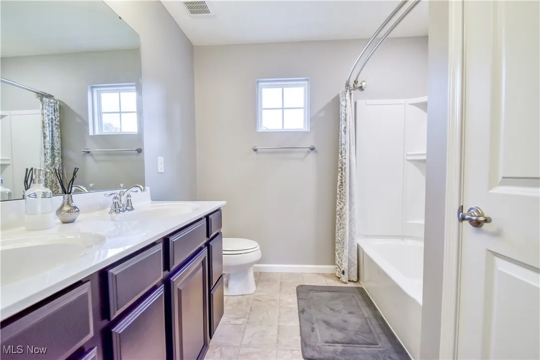 Full bath with double vanity and shower / bathtub combination with curtain