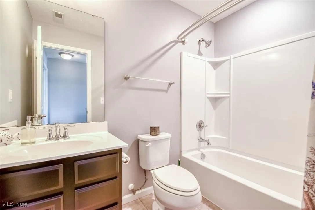 Full bathroom with shower / bath combo with shower curtain, vanity, and light tile patterned flooring