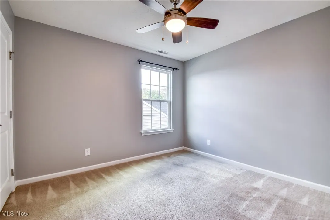 Carpeted empty room featuring baseboards and ceiling fan