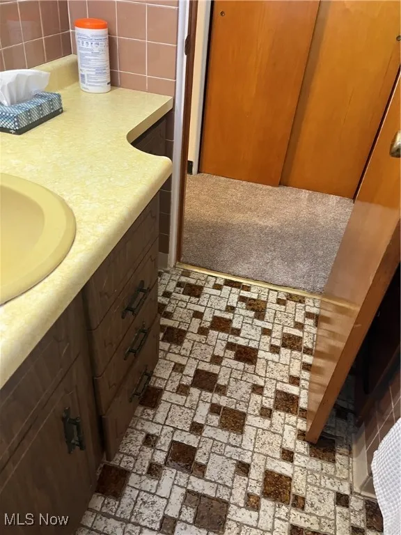 Bathroom with tile flooring, vanity, and tasteful backsplash