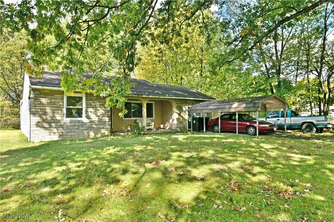 Ranch-style home featuring a detached carport, a front lawn, and a shingled roof