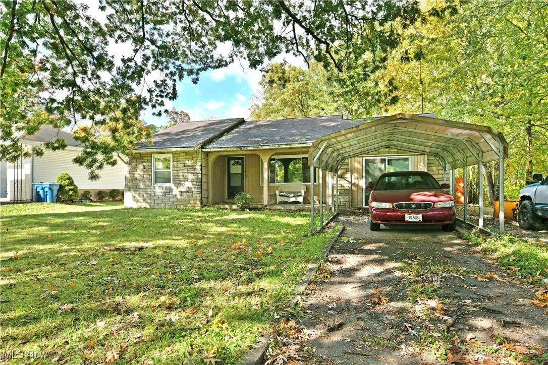 Single story home featuring a front yard, a detached carport, and a porch