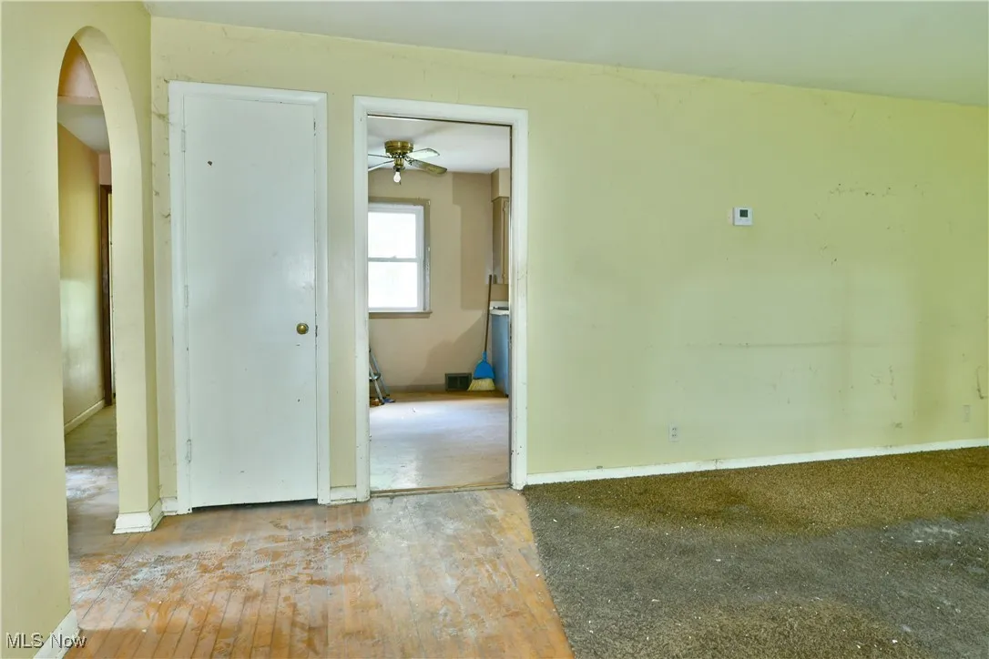 Empty room with hardwood / wood-style floors, arched walkways, and a ceiling fan