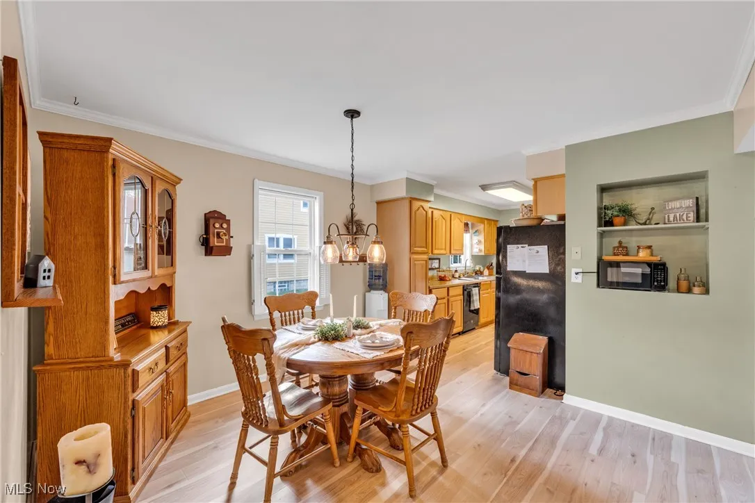 Dining area featuring Pergo light wood-type flooring, ornamental molding, and a chandelier