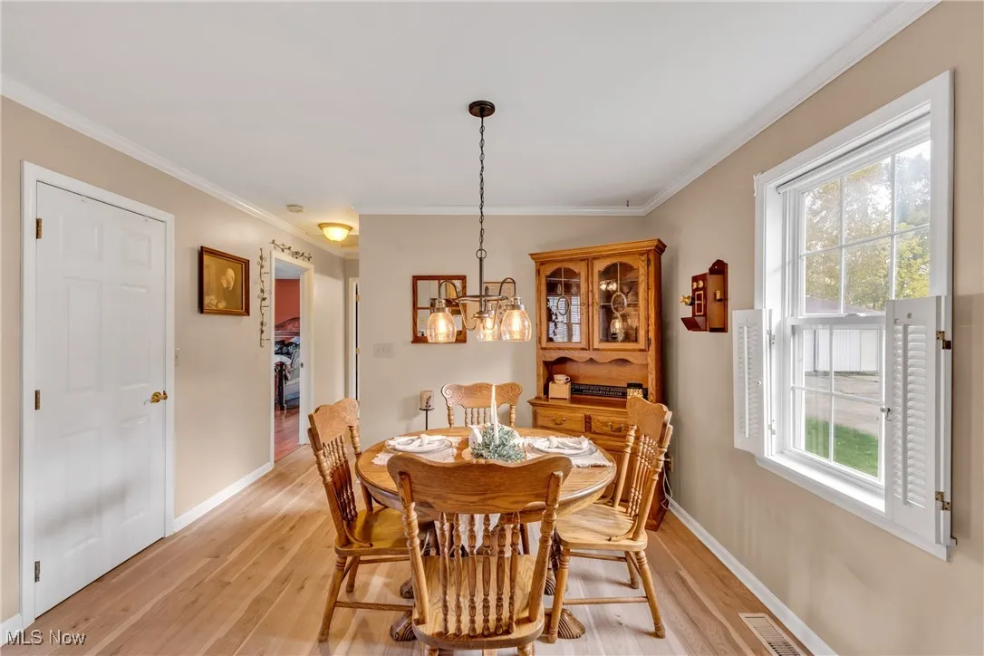 Dining room featuring pergo light wood-type flooring, ornamental molding, and a chandelier