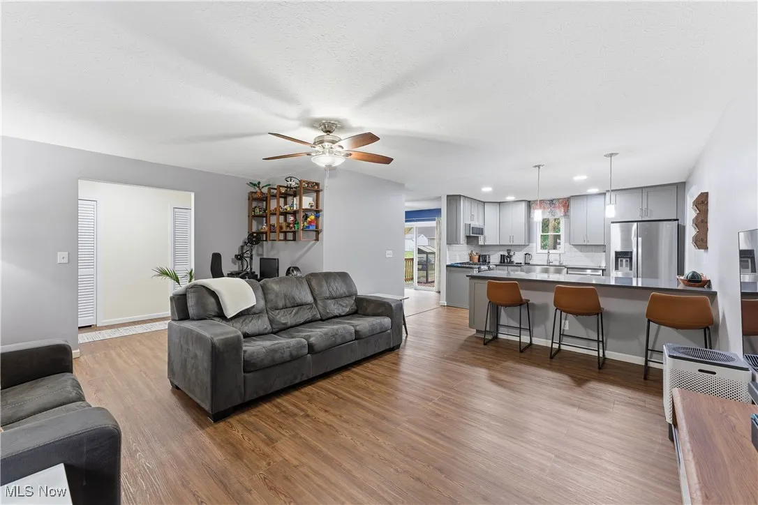 Living room featuring dark wood finished floors, a ceiling fan, a textured ceiling, and recessed lighting