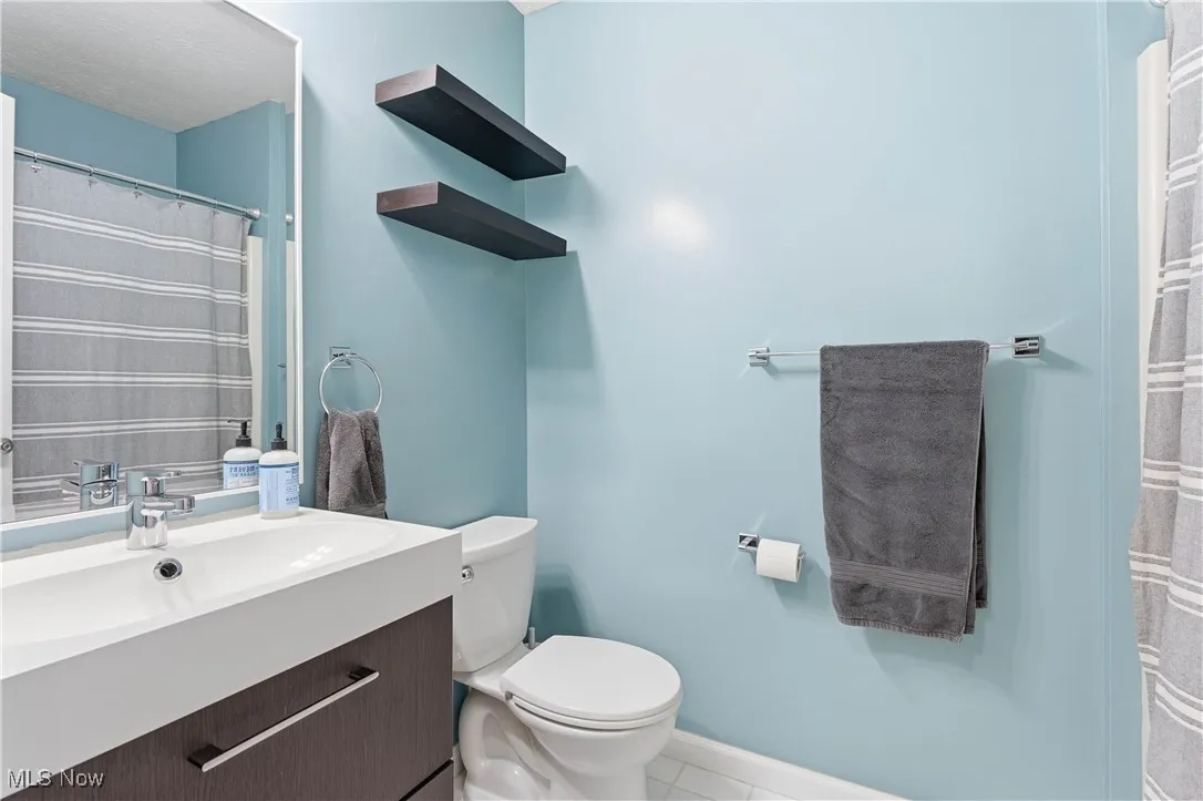 Full bathroom featuring a shower with curtain, vanity, and light tile patterned flooring