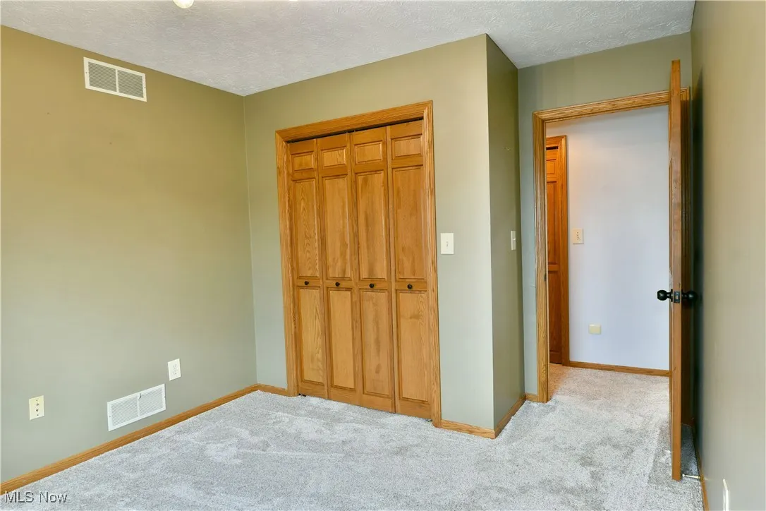 Unfurnished bedroom with a textured ceiling, carpet, and a closet