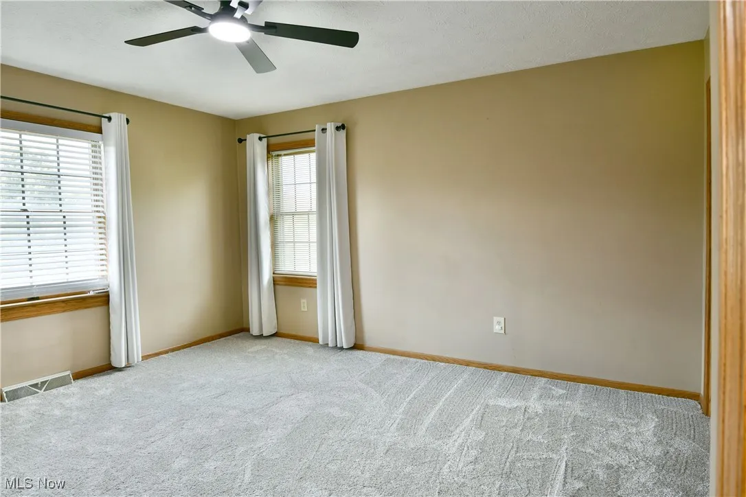 Carpeted spare room with ceiling fan and a textured ceiling