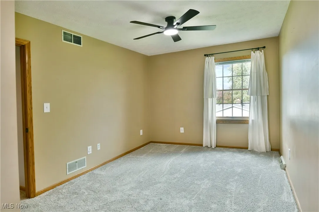 Unfurnished room featuring carpet and a ceiling fan