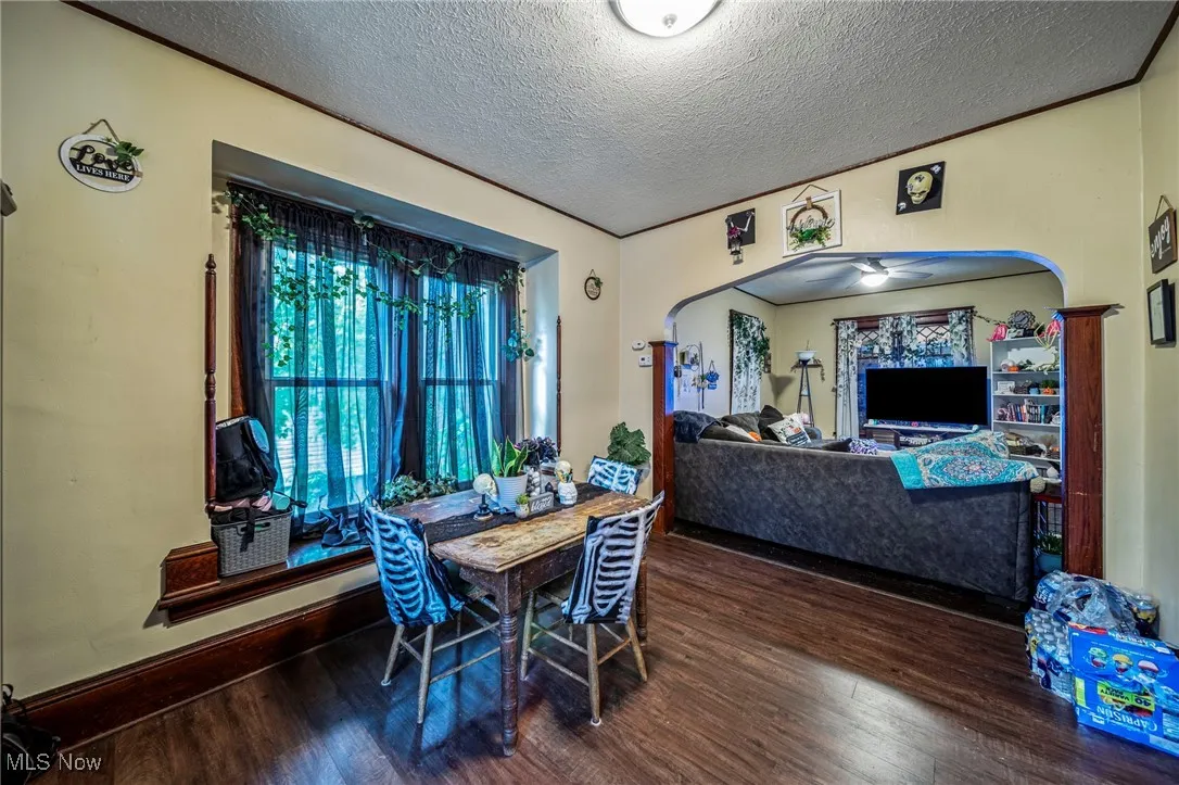 Dining area featuring arched walkways, a textured ceiling, dark wood finished floors, and ceiling fan