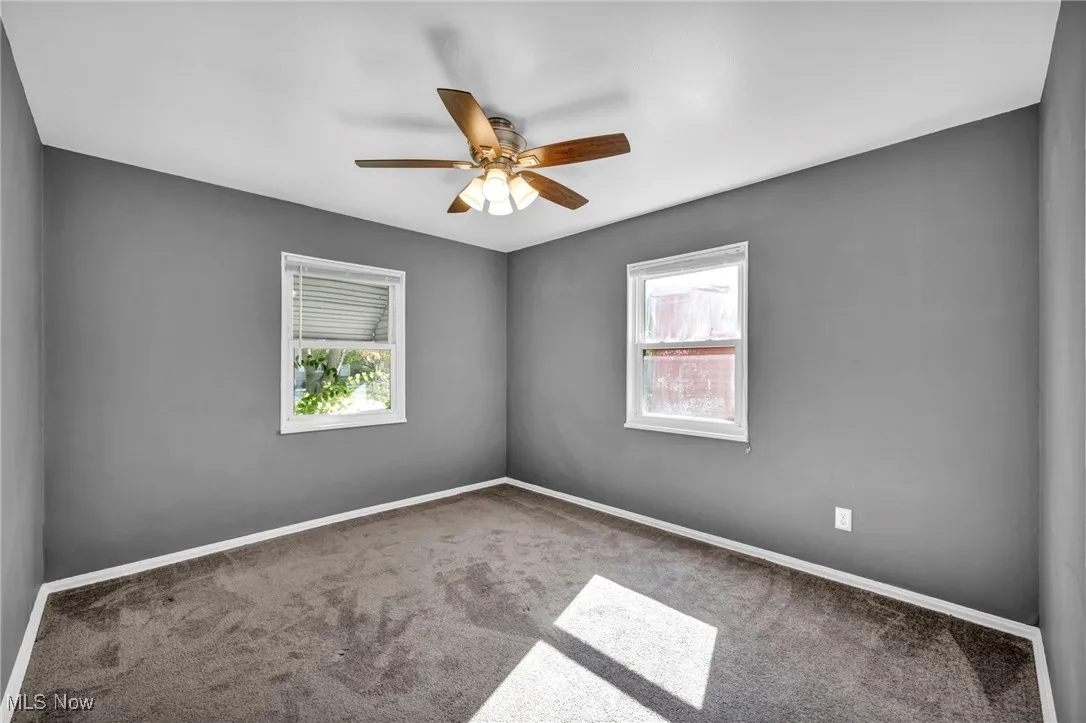 Carpeted spare room with baseboards and ceiling fan