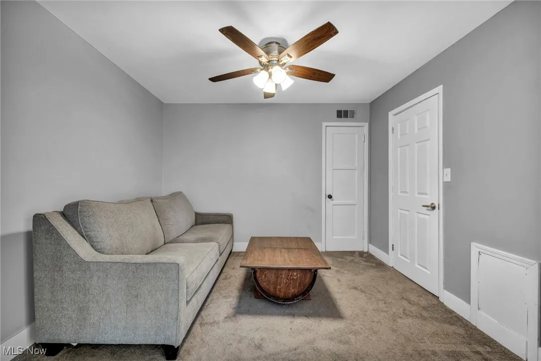 Carpeted living room featuring baseboards and a ceiling fan