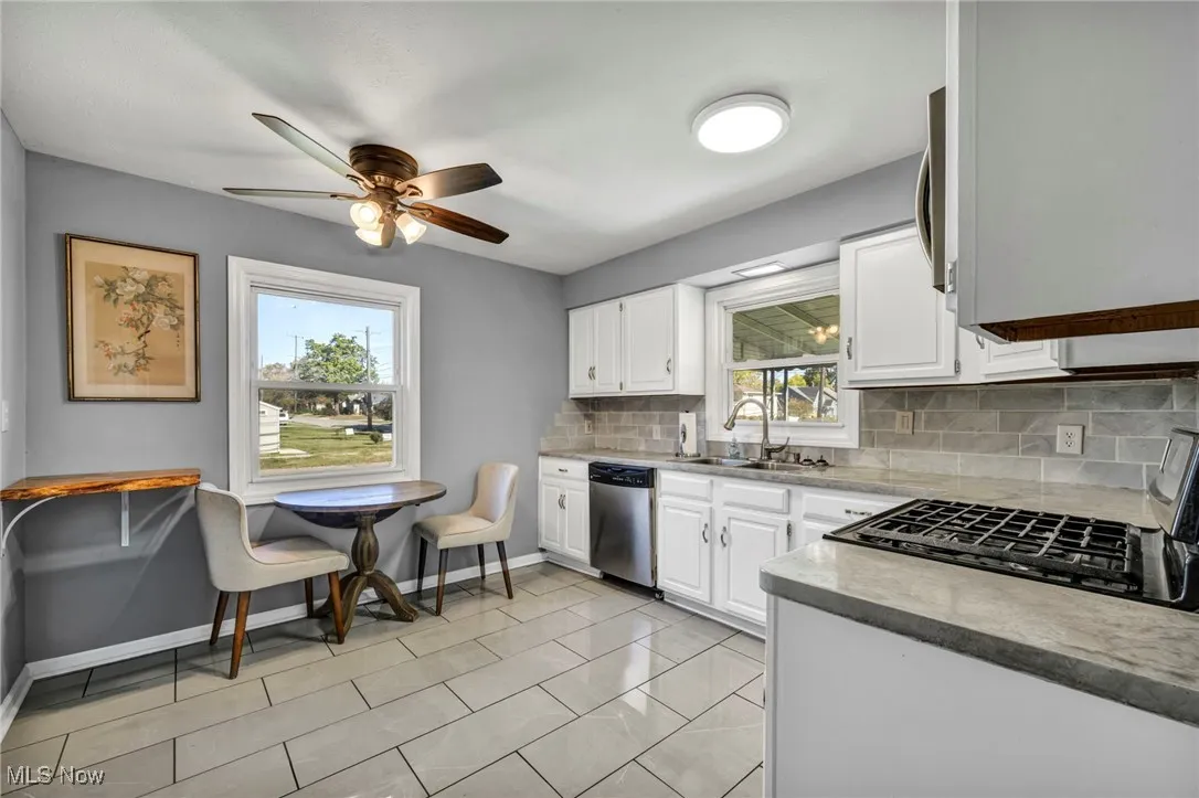 Kitchen featuring backsplash, white cabinetry, appliances with stainless steel finishes, and light tile patterned floors