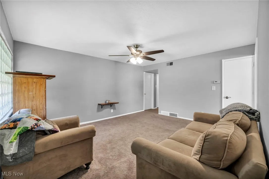 Carpeted living area featuring baseboards and ceiling fan