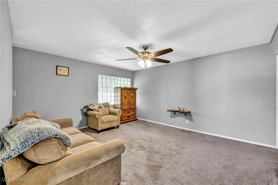 Sitting room with carpet floors, a ceiling fan, and a textured ceiling