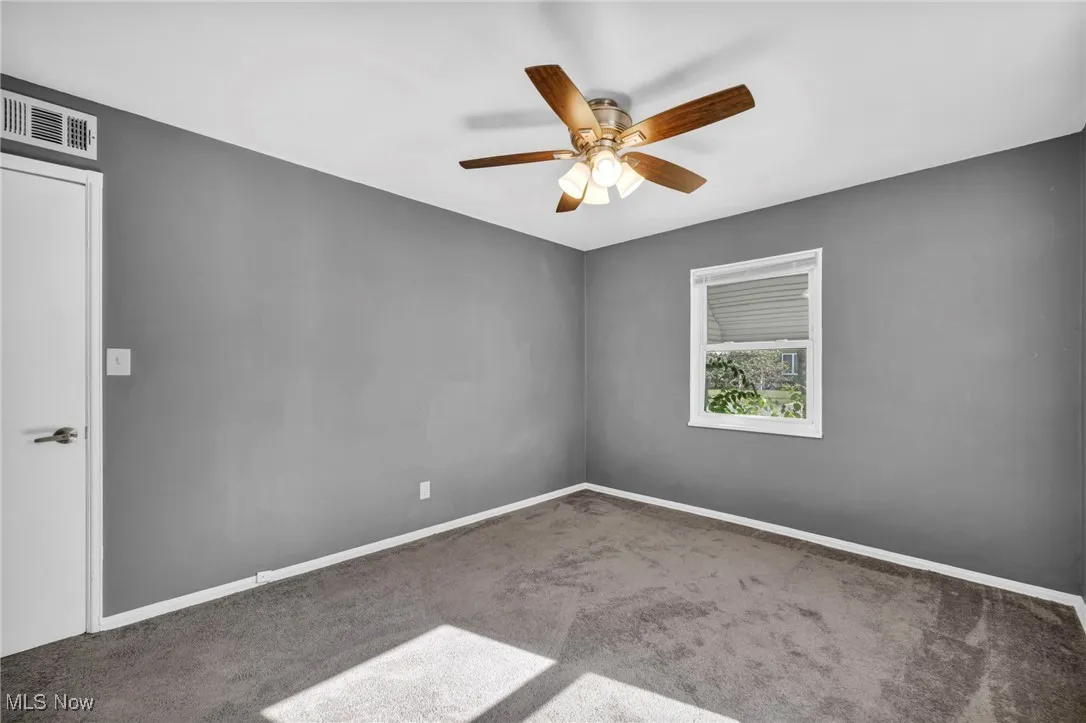 Carpeted spare room with baseboards and a ceiling fan