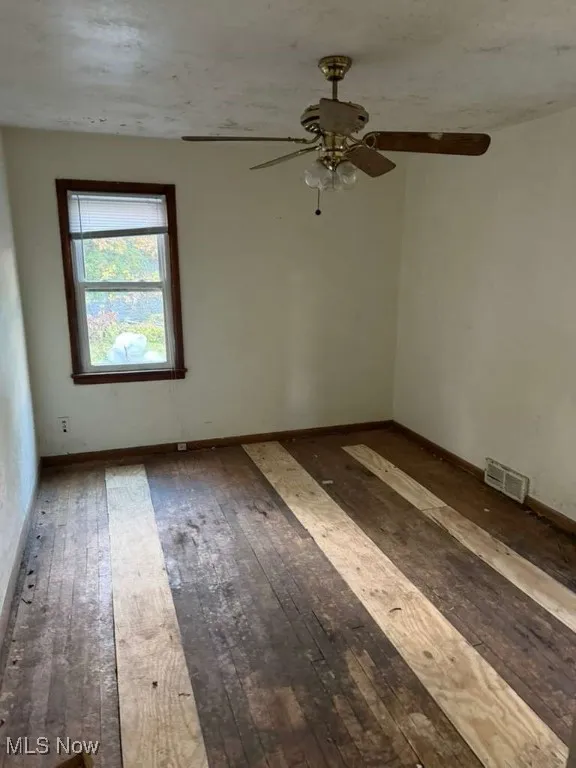 Unfurnished room with dark wood-type flooring and ceiling fan