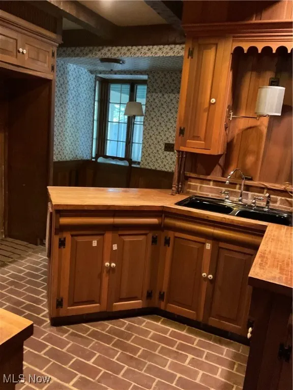 Kitchen with wooden counters, brick patterned floors, and showing breakfast area.