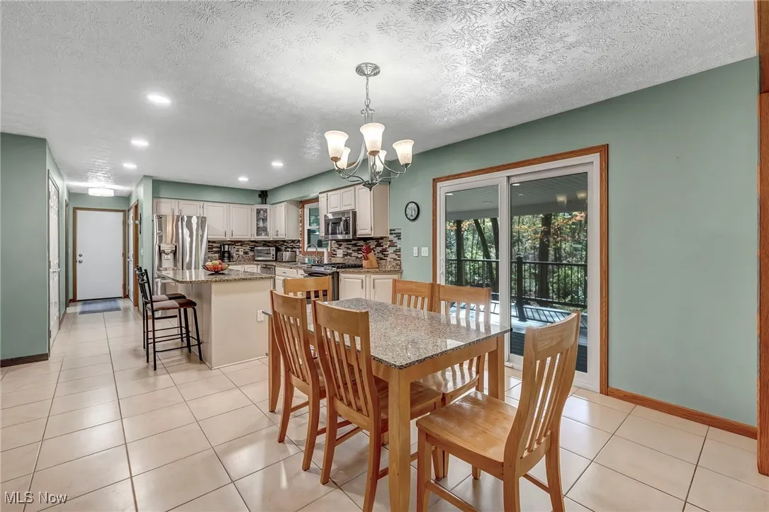 Dining room featuring a chandelier, light tile patterned floors, a textured ceiling, and recessed lighting