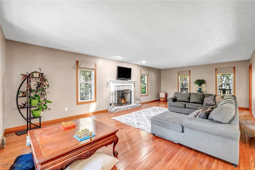 Living room with light wood-style flooring, a textured ceiling, a fireplace, and plenty of natural light