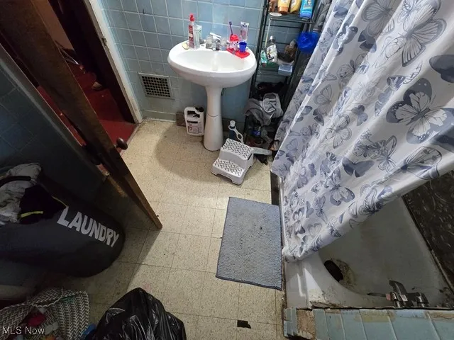 Full bathroom with tile walls and a shower with curtain
