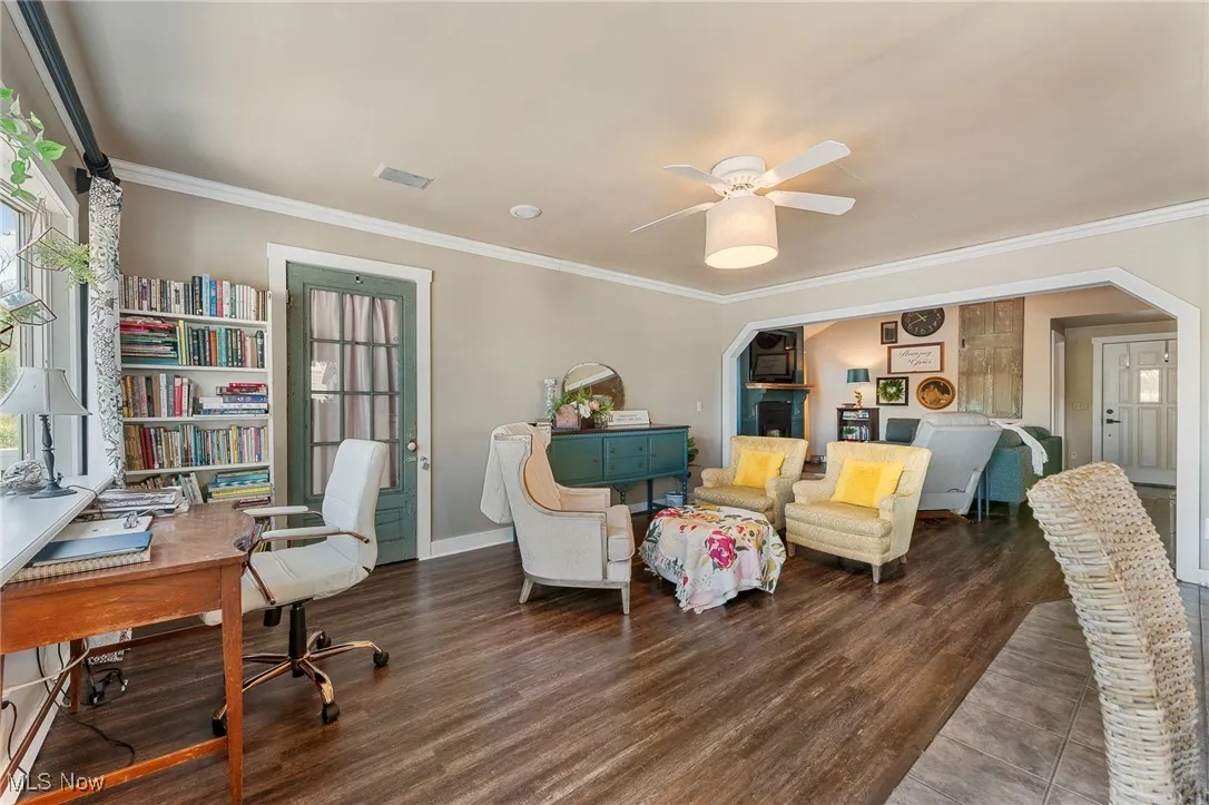 Home office with arched walkways, room for a sitting area, ornamental molding, dark wood-style floors, and ceiling fan