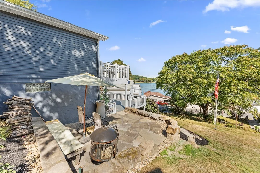 Patio / terrace with a patio area, an outdoor fire pit, a yard, and a water view