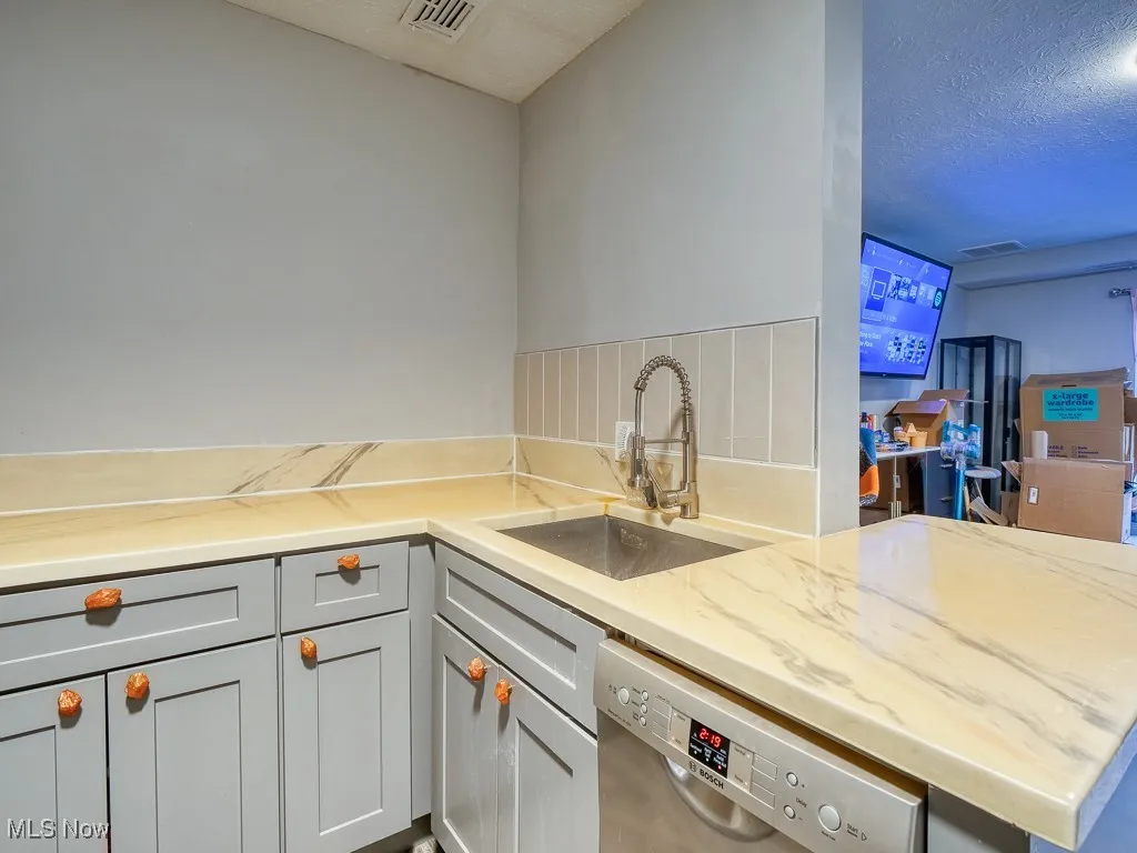 kitchen featuring gray cabinets and faux marble countertops with under mount stainless steel sink