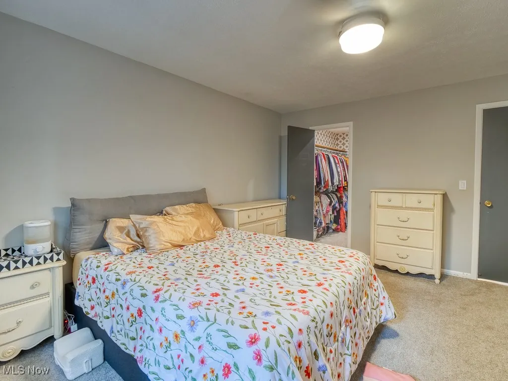 bedroom with light colored carpet and walk in closet