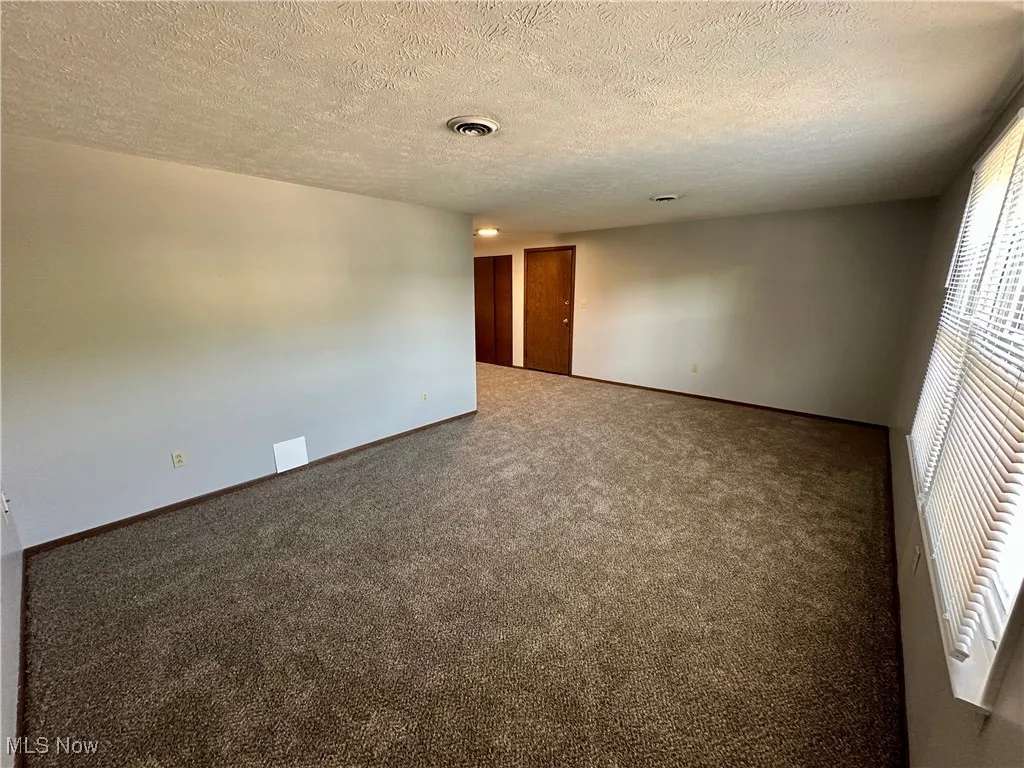 Unfurnished room featuring carpet flooring and a textured ceiling