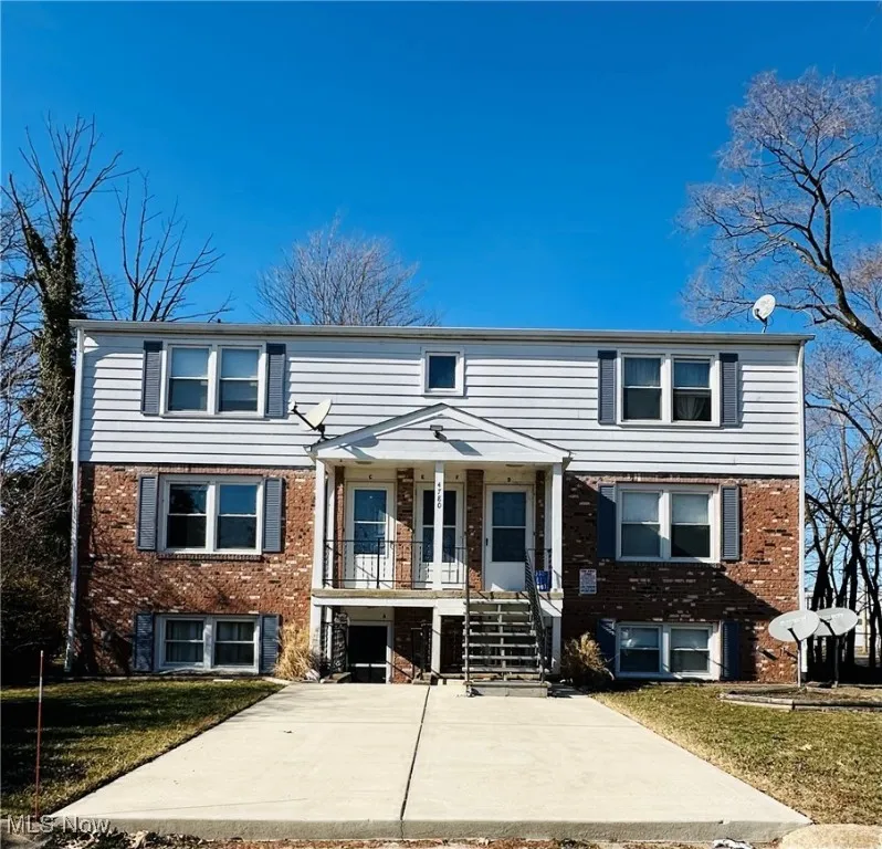 View of front of property featuring brick siding, a front yard, and a balcony