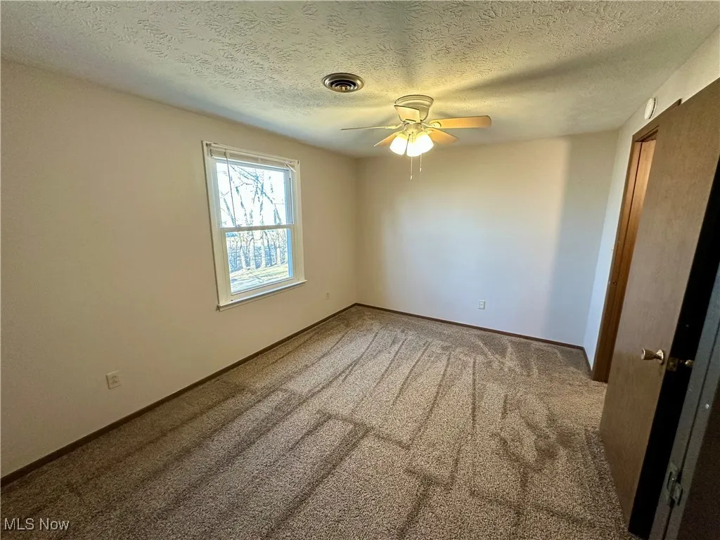 Unfurnished room with carpet floors, a textured ceiling, and a ceiling fan